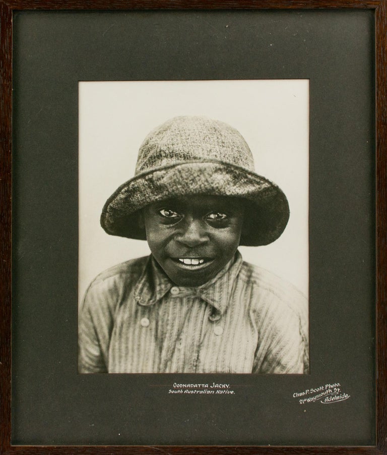 Item #108084 'Oodnadatta Jacky - South Australian Native'. A charming vintage portrait photograph of a young Aboriginal boy wearing a large cloth hat and an even bigger grin. Indigenous Australian Portraiture, Charles P. SCOTT.