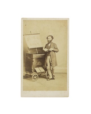 Item #114879 A carte de visite of a musician and his small portable organ on a four-wheeled...