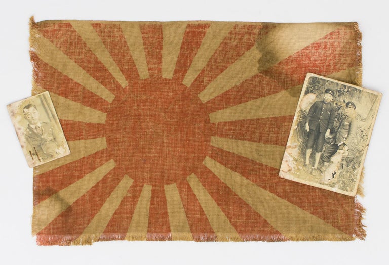 Item #115364 A small Japanese flag (linen, approximately 210 × 310 mm) and two snapshots of Japanese men. One shows two men in military uniforms, holding hands (they may be brothers); the other appears to show the older man in civilian clothing. These three items are waterstained, the photographs are mottled, and the larger one has some paper residue on its surface, but they may well have been salvaged from the battlefield, and as such have considerable emotional impact. Japan.