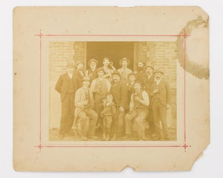 A vintage photograph of staff at Chateau Tanunda Winery in the Barossa Valley, South Australia; most of them are raising glasses of house wine, and those seated are on barrels