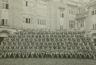 A group portrait featuring approximately one hundred soldiers in what appears to be the quadrangle of a public building, presumably in England