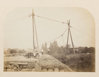 A vintage photograph showing a very large artillery piece being manoeuvered into position with an intricate block-and-tackle system
