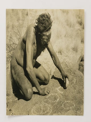 A vintage photograph of an Indigenous Australian man producing rock art near Mount Conner in 1940