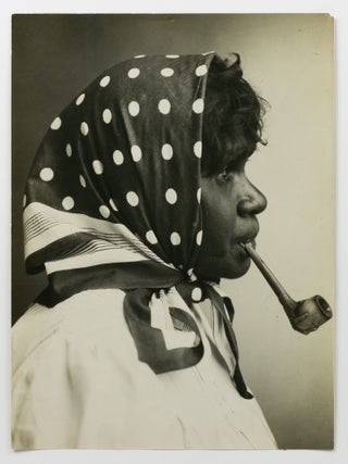 An imposing large-format portrait photograph of Clara, a young Central Australian Indigenous woman, smoking a pipe (circa 1900s)