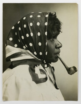 An imposing large-format portrait photograph of Clara, a young Central Australian Indigenous woman, smoking a pipe (circa 1900s)